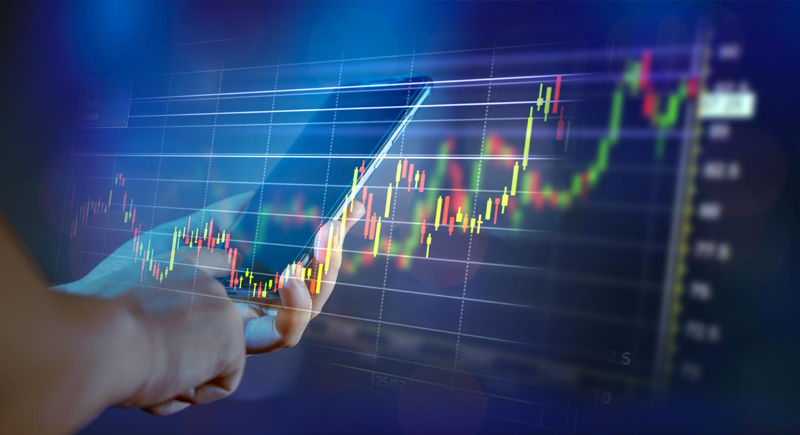 financial graphs on transparent screen with hand holding phone in background
